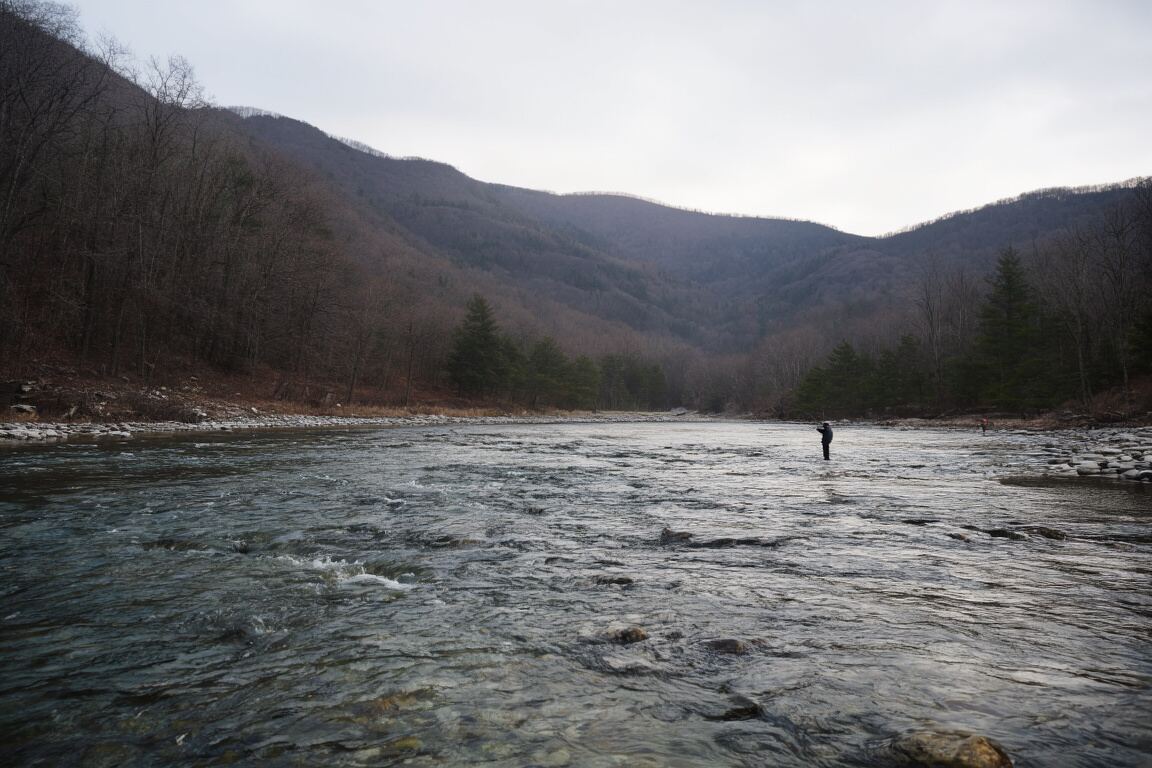 A quiet gravel access road leading toward a wooded river bend at low light, prepared for the East Tennessee fly fishing field note